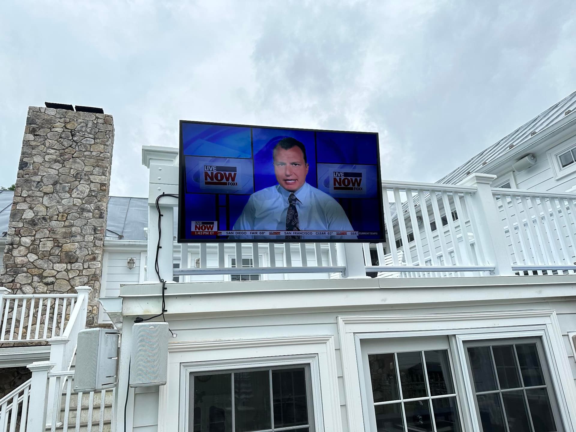 Large outdoor TV mounted on residential deck