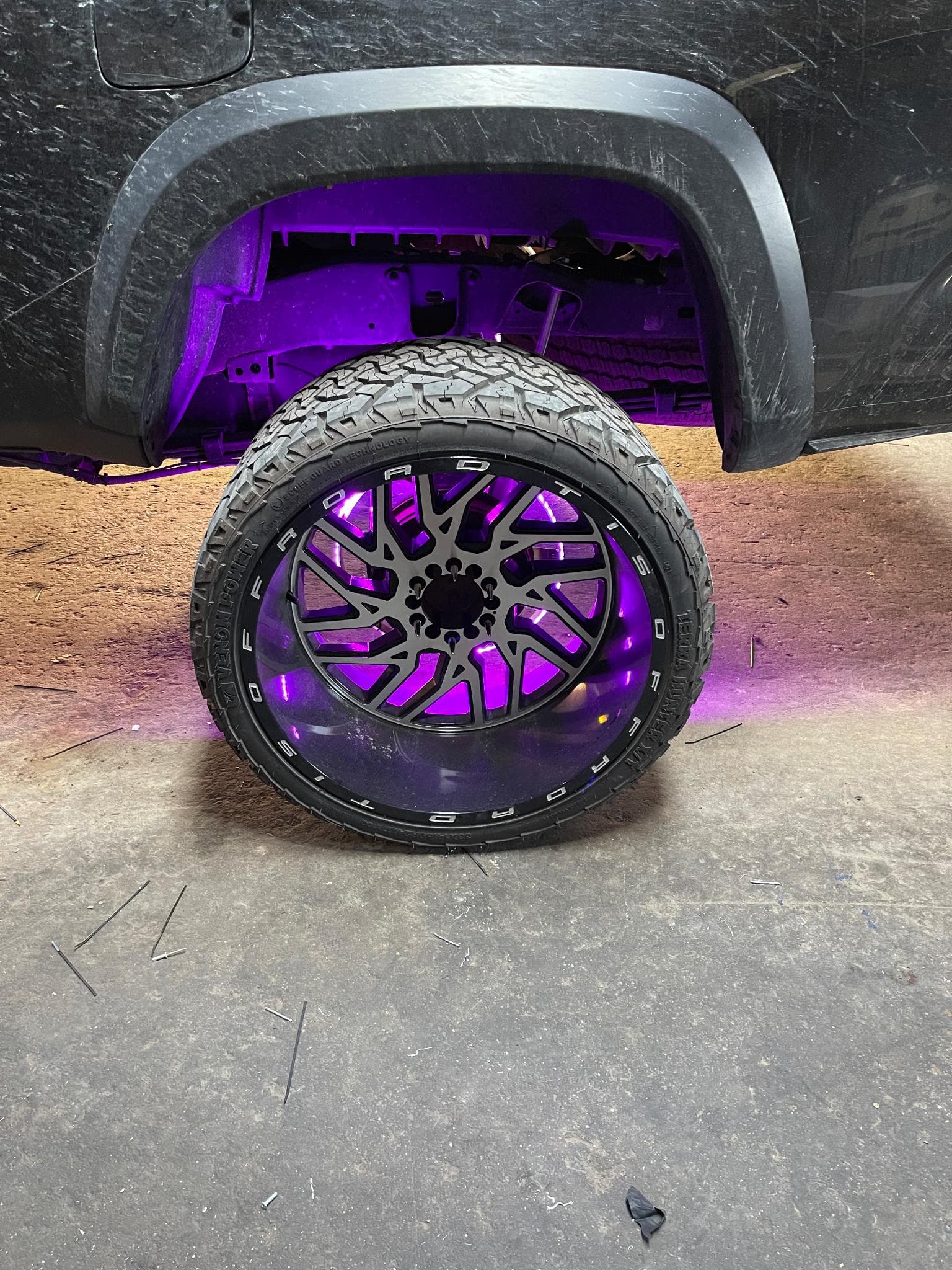 Purple LED wheel well lighting illuminating a truck tire at night